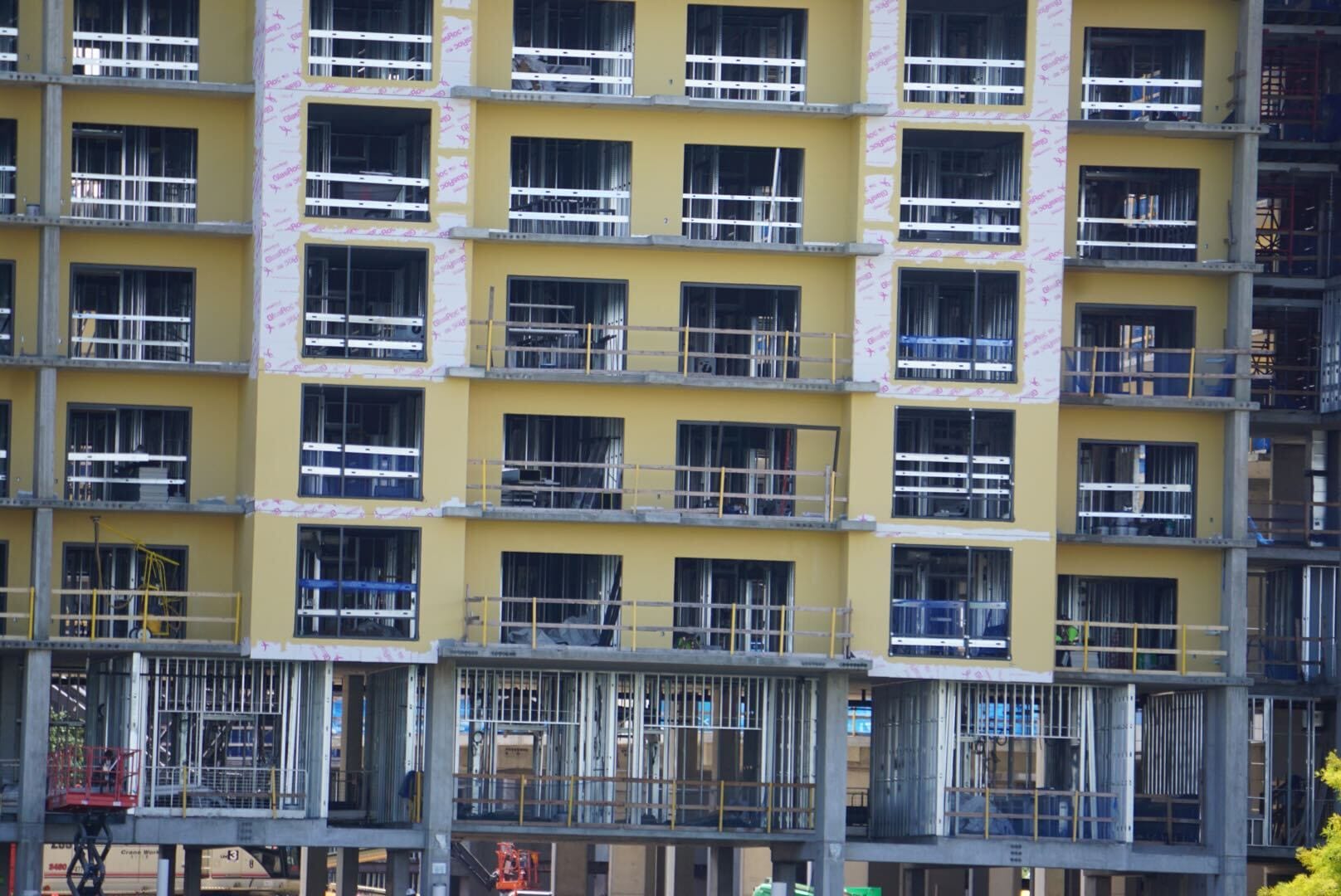 A multi-story building under construction with yellow exterior walls and exposed metal framework.