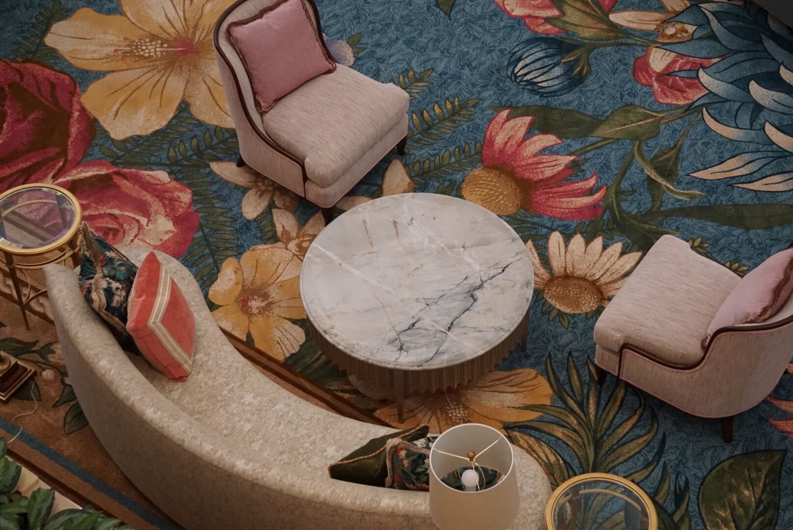 A marble coffee table with lobby furniture rests on a floral blue carpet at Disney’s Grand Floridian Resort, evoking classic park elegance.