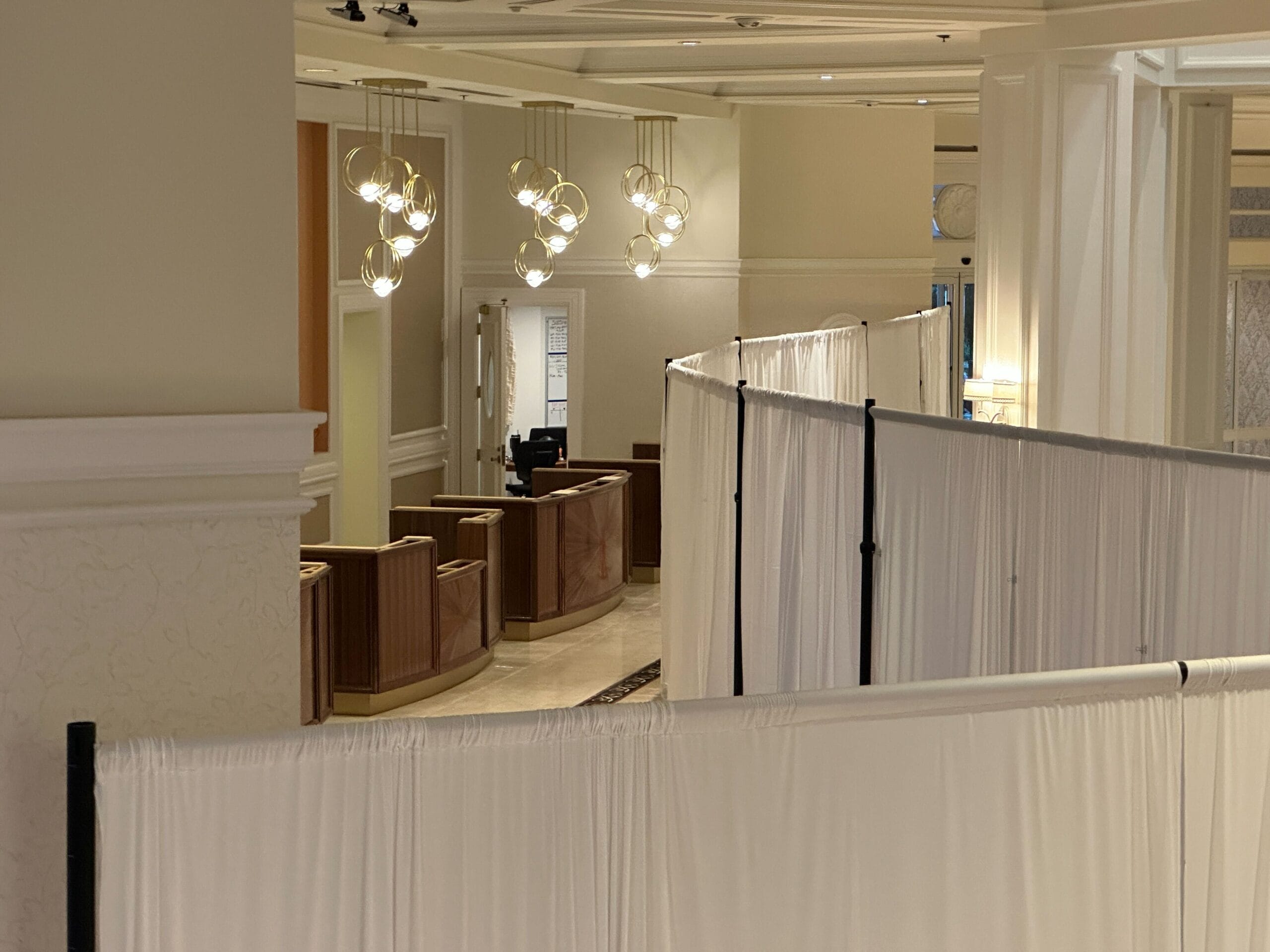 A Grand Floridian hotel lobby with white temporary partition curtains and modern hanging light fixtures.