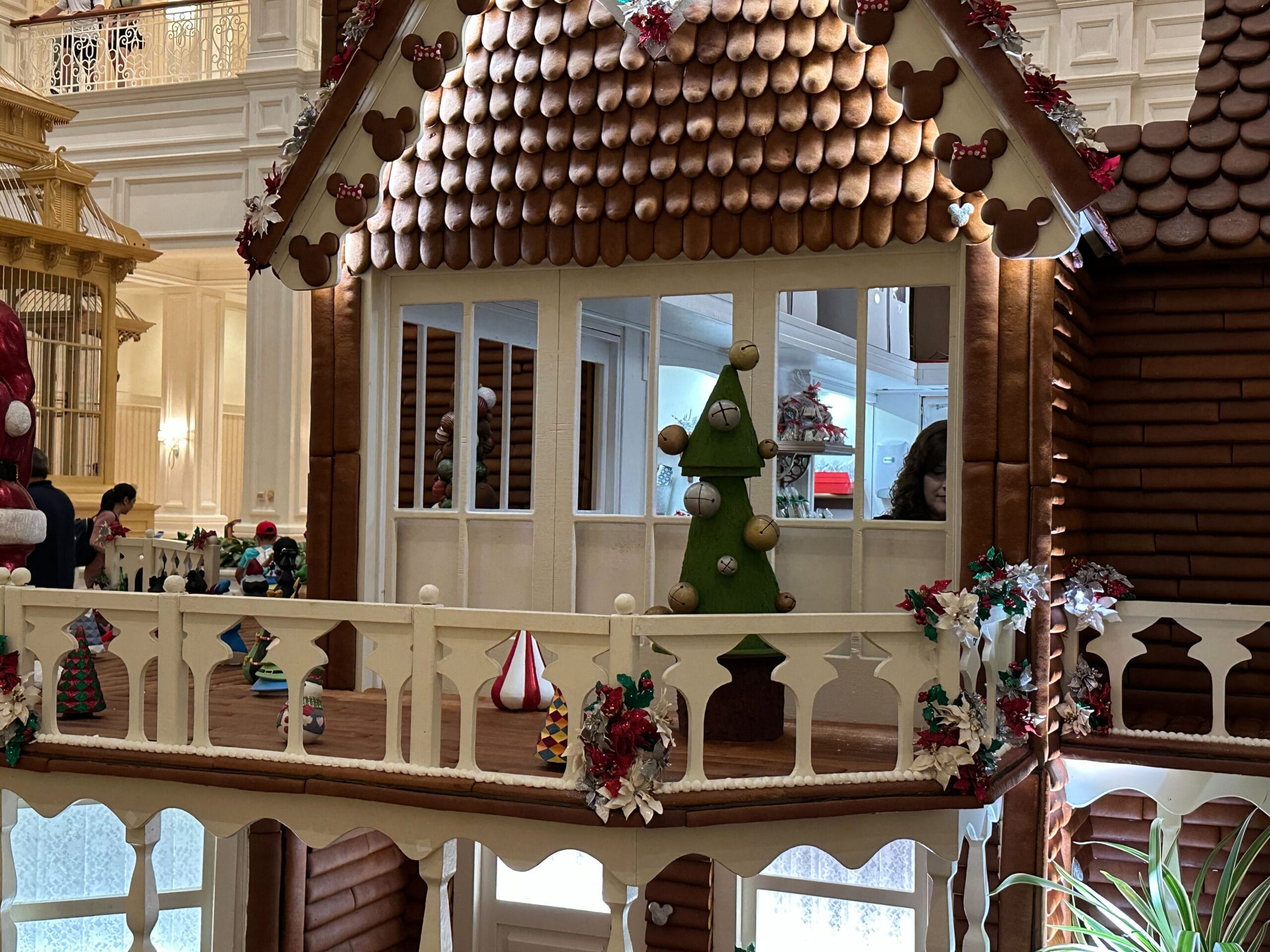 A detailed gingerbread house with decorative rooftop and balcony, featuring Christmas ornaments and a small tree.