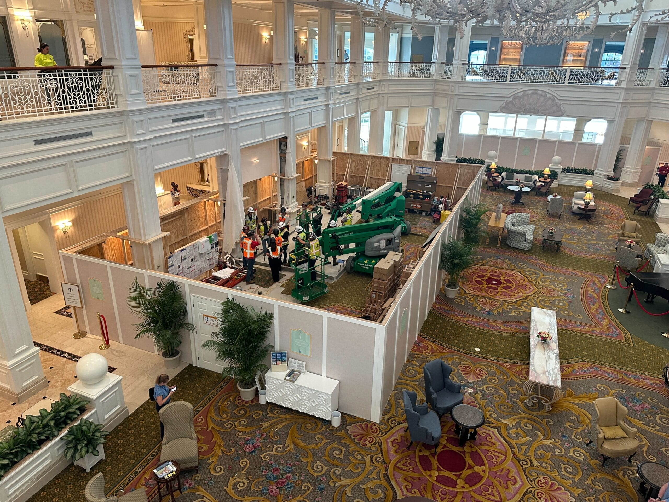 Grand Floridian lobby area with ornate decor; central section under construction with workers and equipment behind temporary walls.