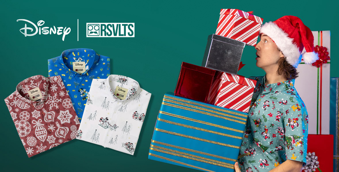 At left in profile is a man wearing a Santa hat and a holiday RSVTS short-sheeve shirt. He holds a pile of wrapped presents that are about to tip over. At left are three RSVTS shirts with holiday-inspired prints. The logo Disney| RSVTS is at top. 