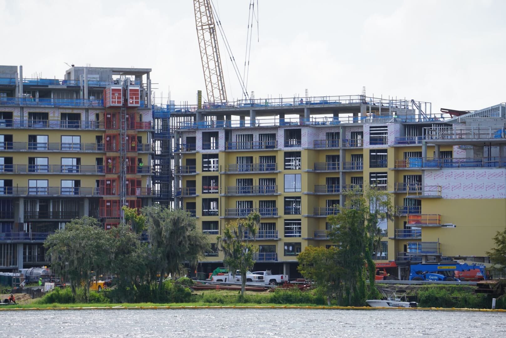 Construction Updates: Multi-story Lakeshore Lodge rising by the water, cranes and materials on site.