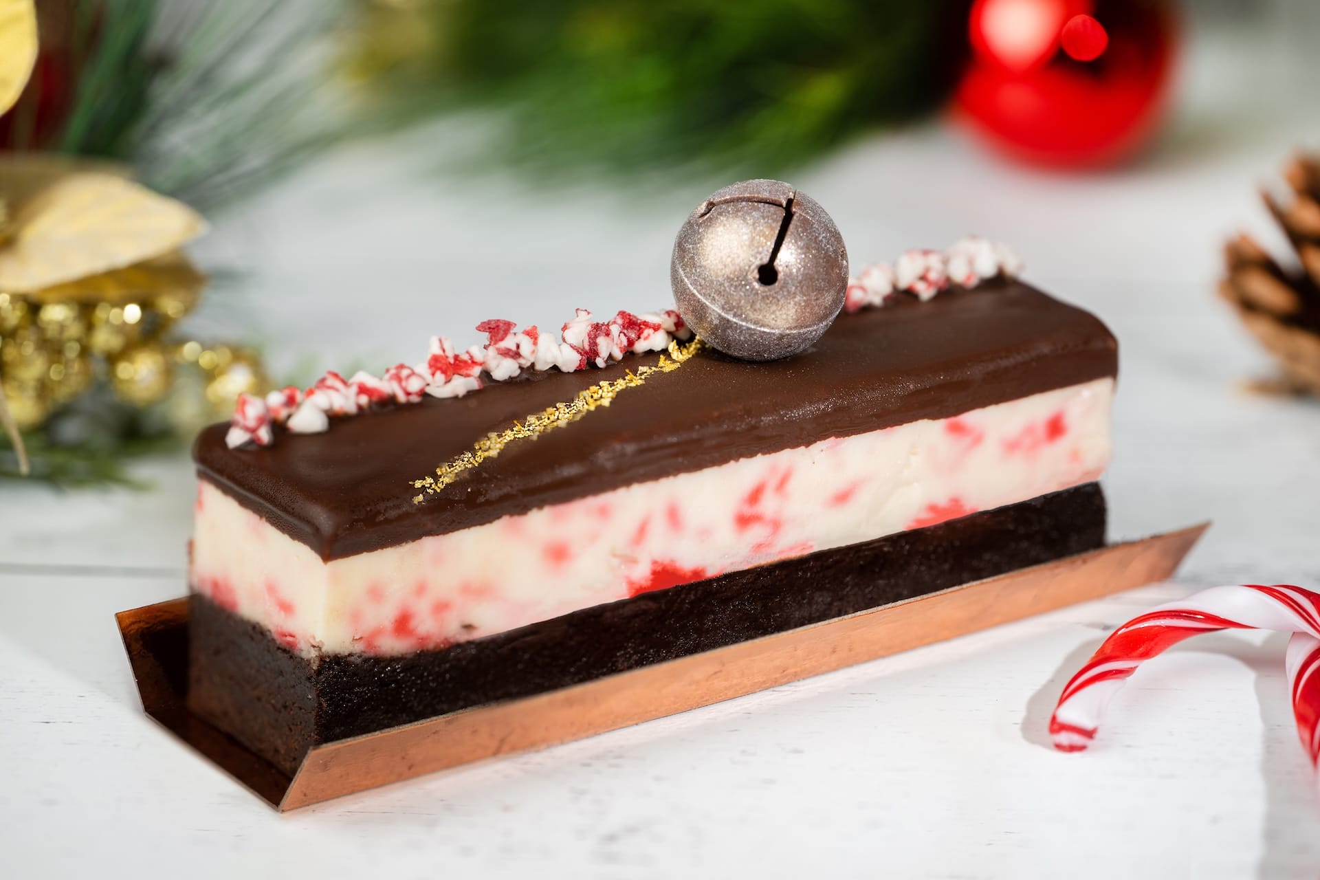 A magical chocolate and peppermint cake, sparkling with gold glitter, crushed peppermint, and a silver bell like Disney holiday treats.