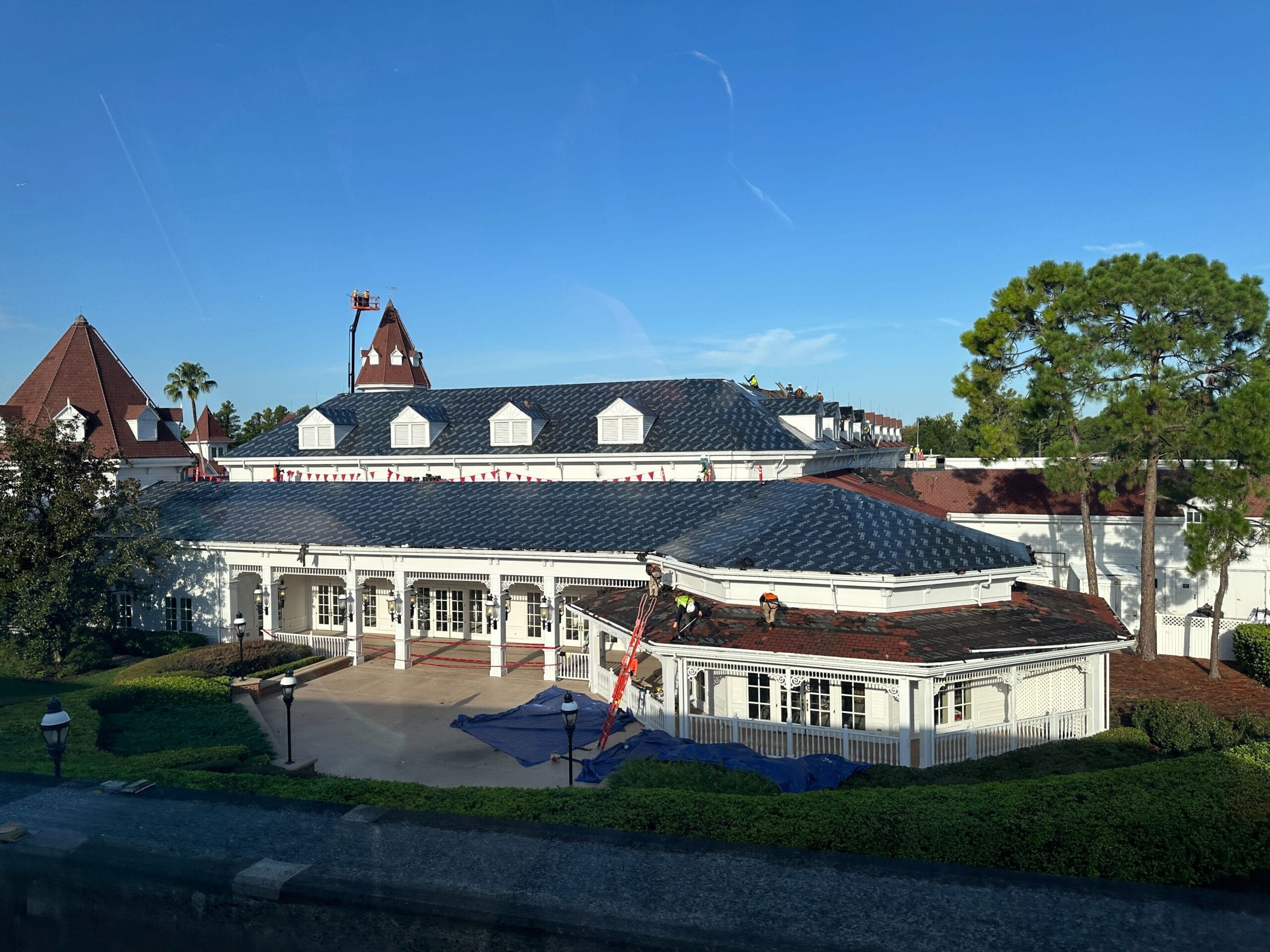 Grand Floridian Convention Center building with torn-up roof, flags, and clear sky, surrounded by trees at this Disney resort.
