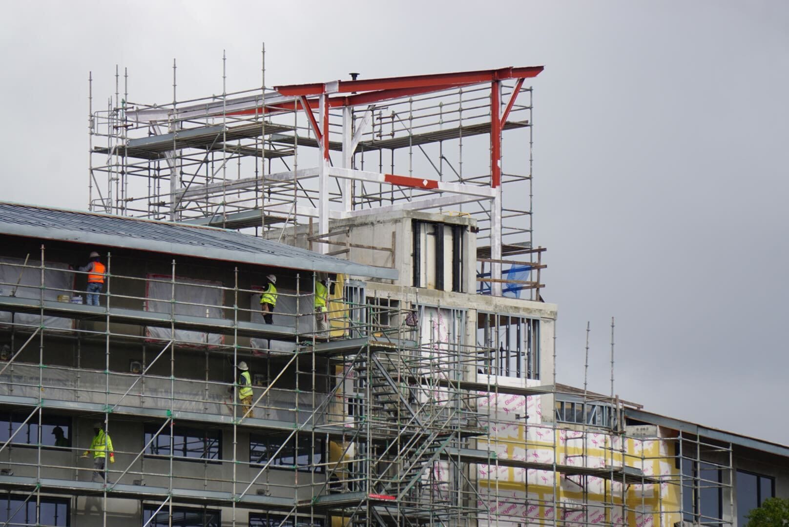 Construction Updates: Workers in safety gear build scaffolding around the rising Lakeshore Lodge.