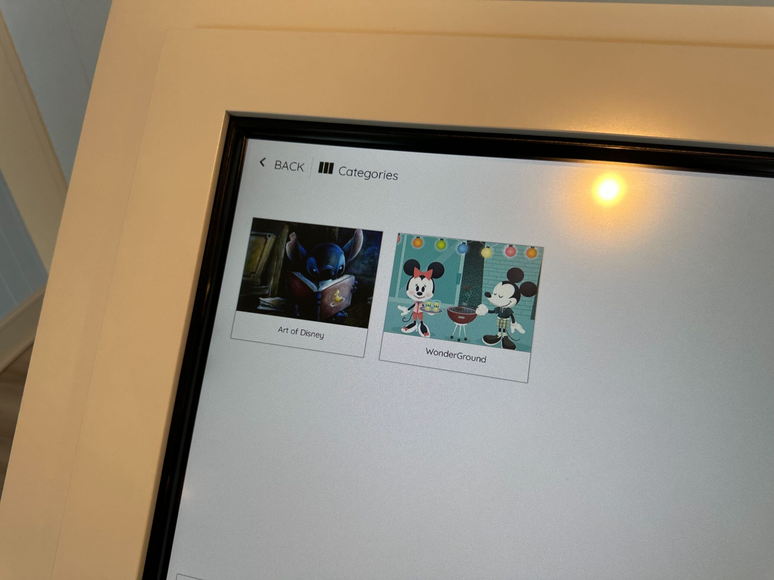 A screen at Disney's Boardwalk Inn Resort showcases two gallery categories: Art of Disney, featuring a dark character image, and WonderGround, highlighting two charming cartoon mice, much like the whimsical finds at the Screen Door General Store.