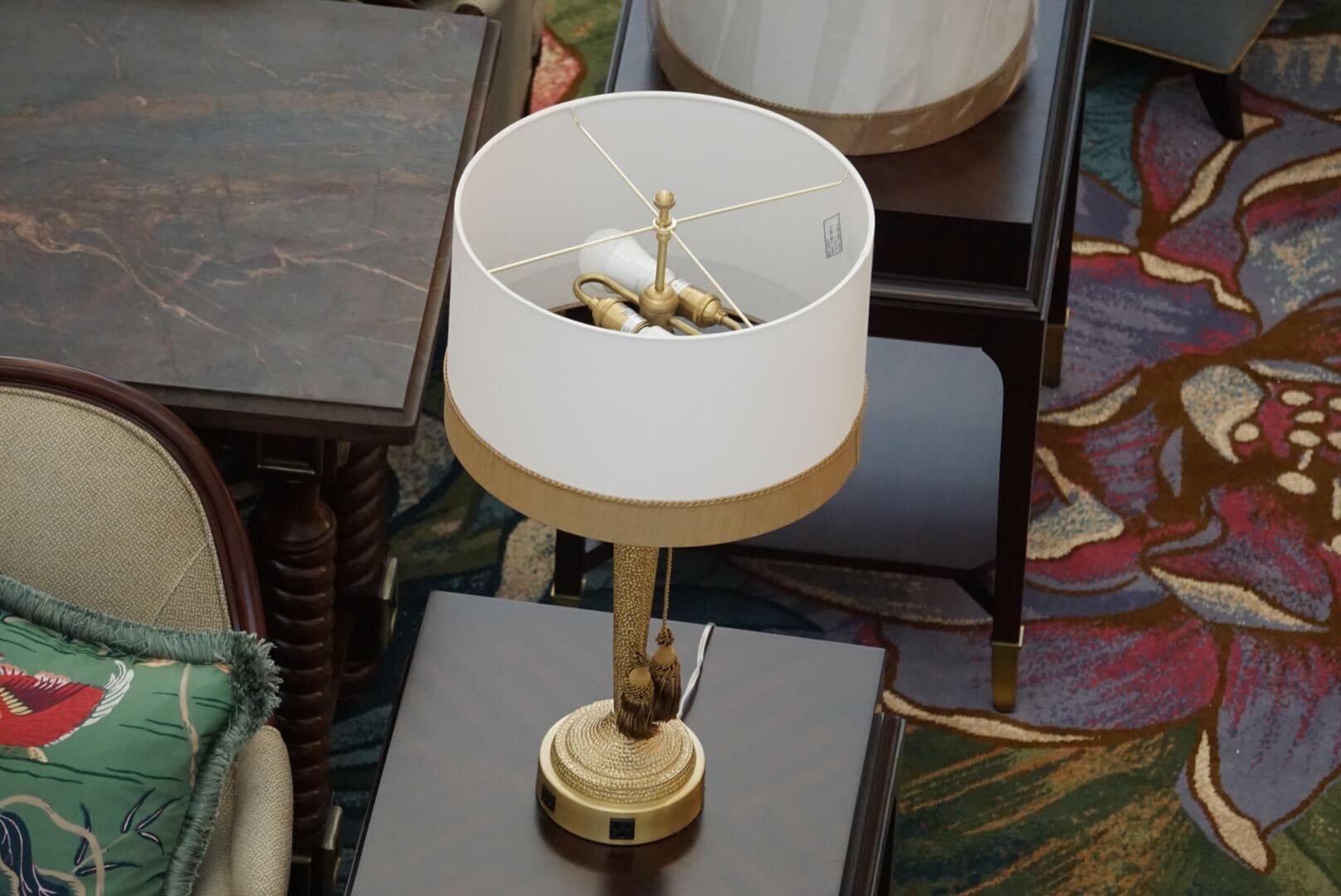 A gold table lamp with a white shade sits on dark wood, enhancing floral lobby décor at Disney's Grand Floridian Resort—no castle in view.