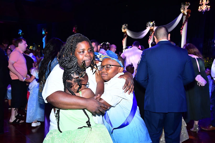 Three school age siblings hug while waiting to meet more Disney princesses.