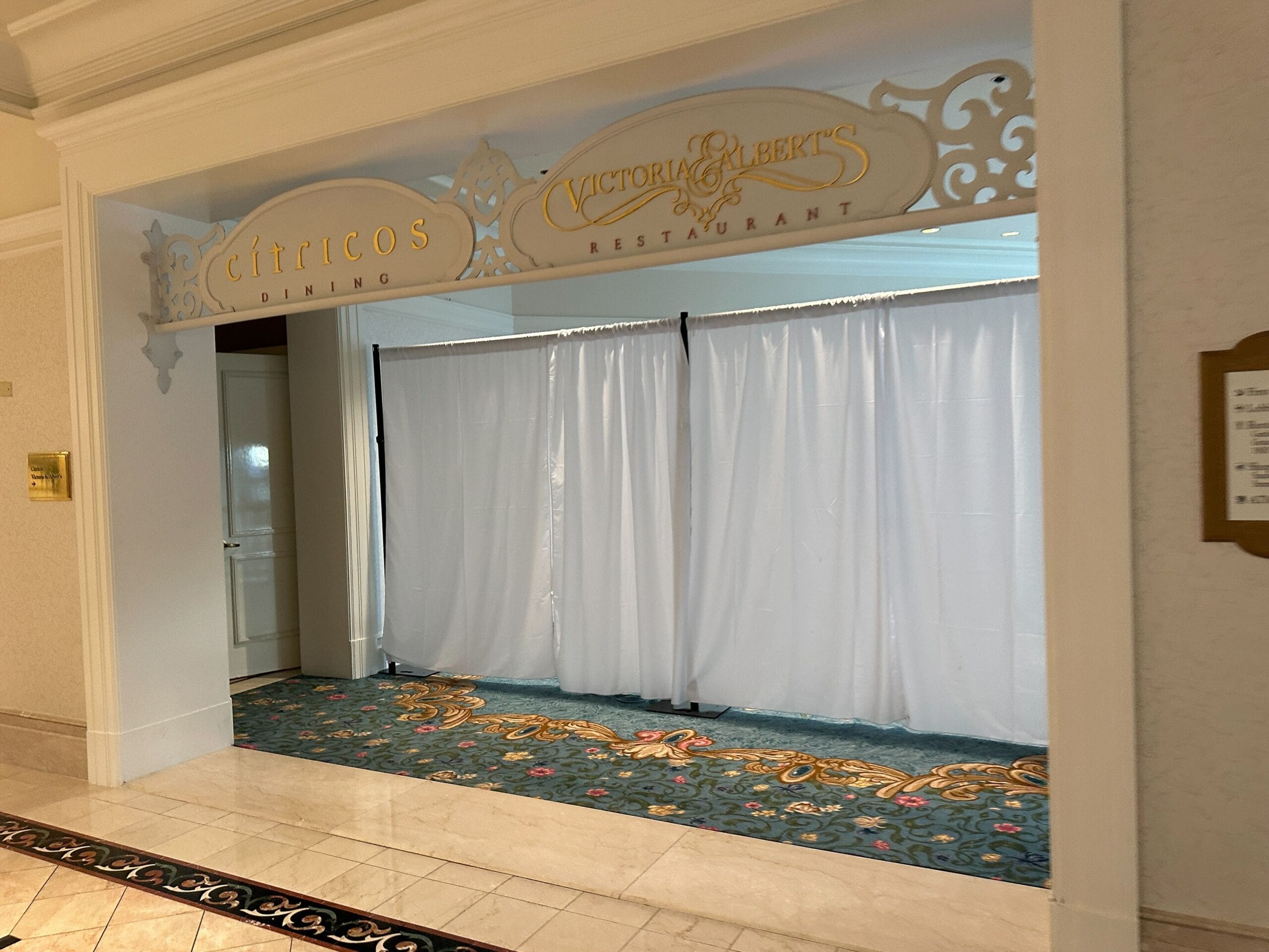 Entrance to Citricos and Victoria & Albert’s restaurants, covered by white curtains with decorative signs above.