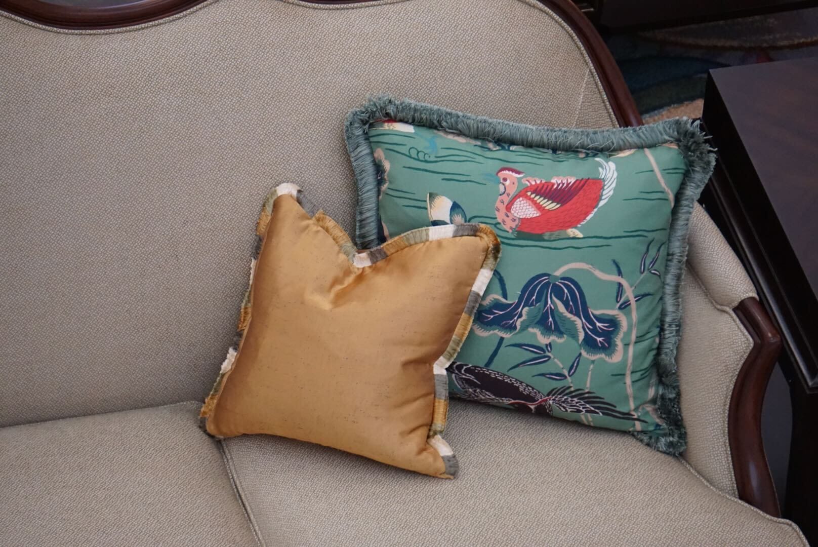 Two decorative pillows on a lobby sofa at Disney’s Grand Floridian Resort; gold and bird-print with fringe, elegant Disney style.