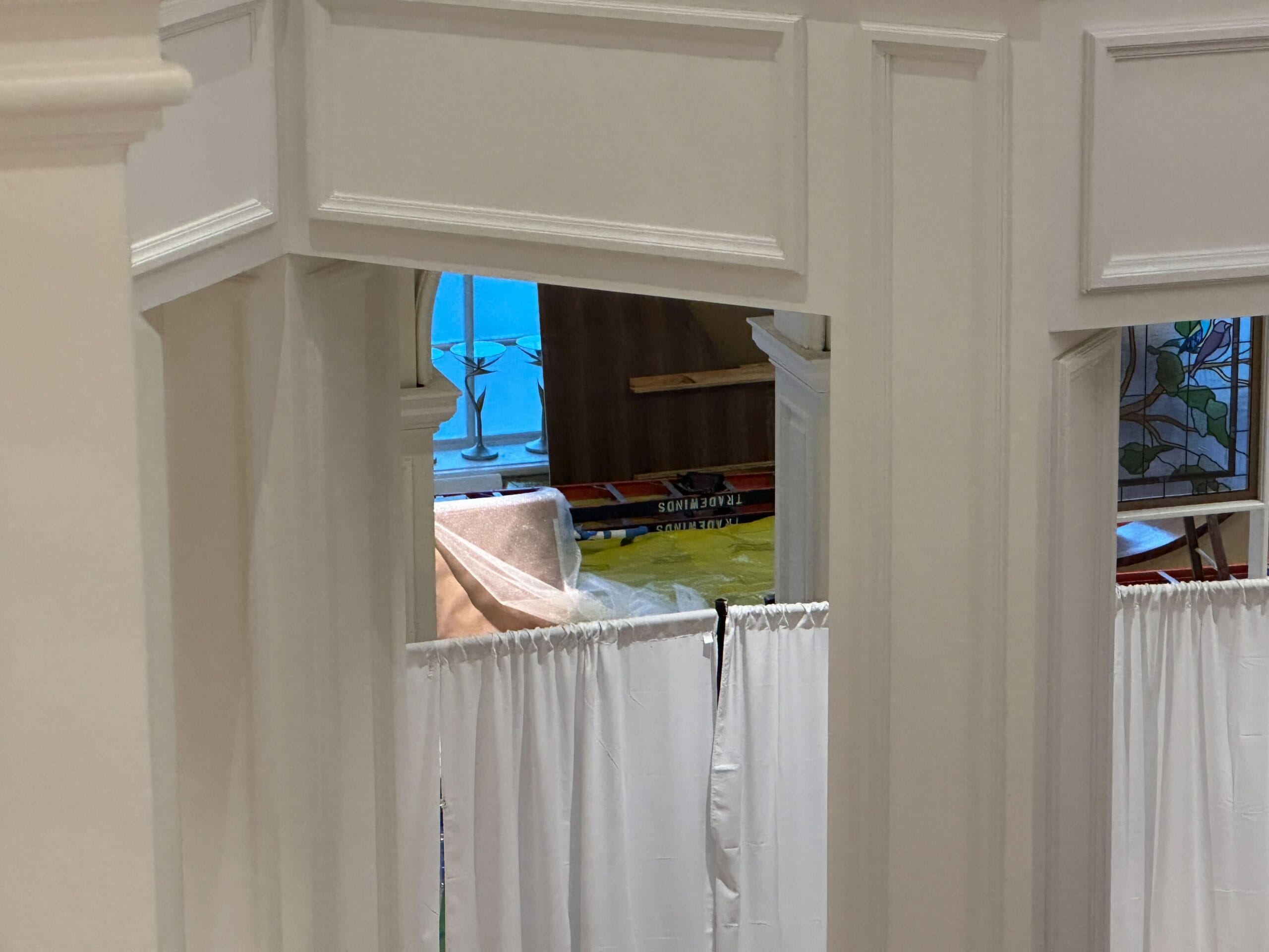 Partially obscured room under Grand Floridian construction with white curtains and building materials, evoking classic Disney elegance.