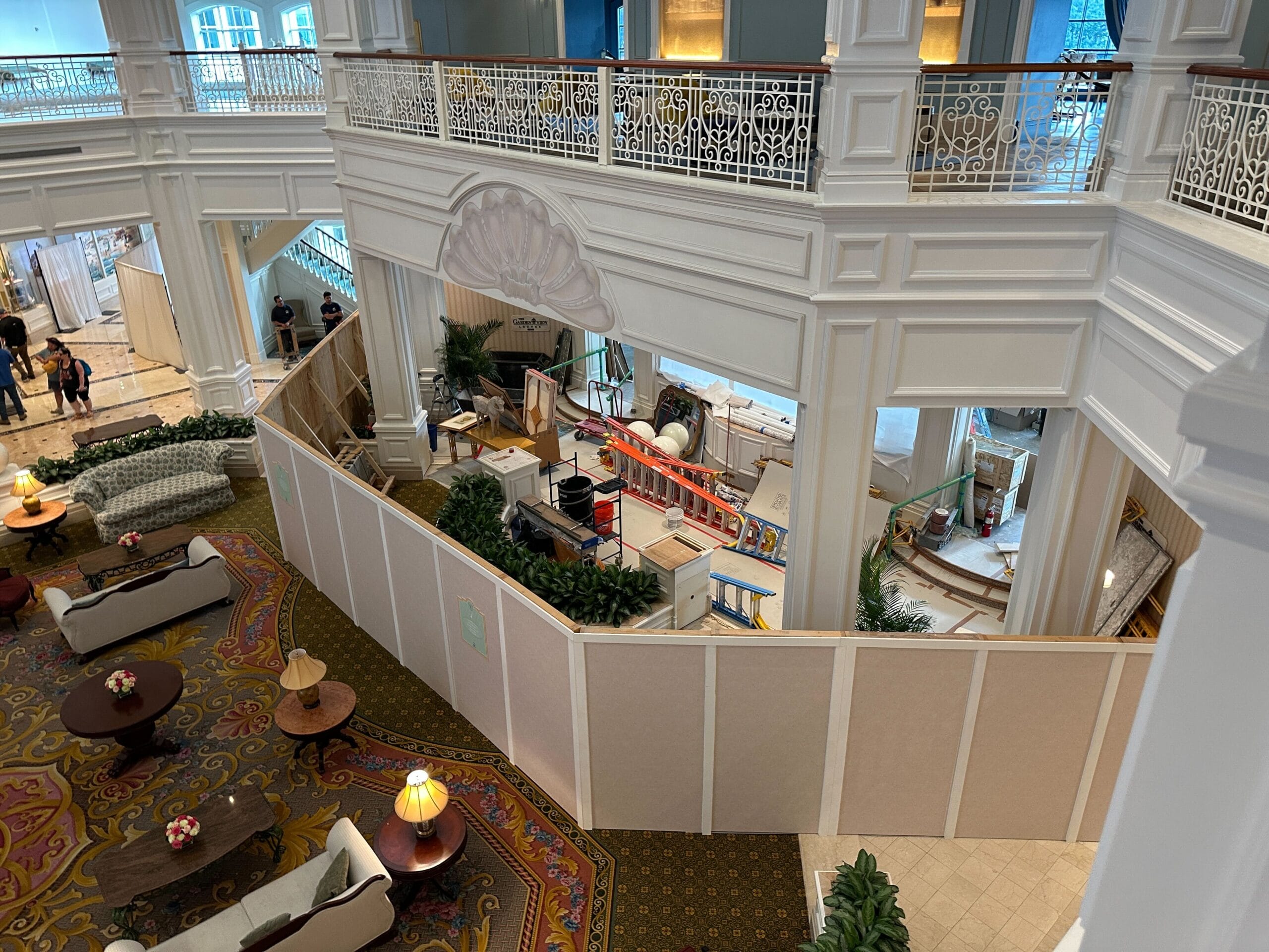View of a hotel lobby with a construction barrier enclosing a section, surrounded by elegant furniture and decor.