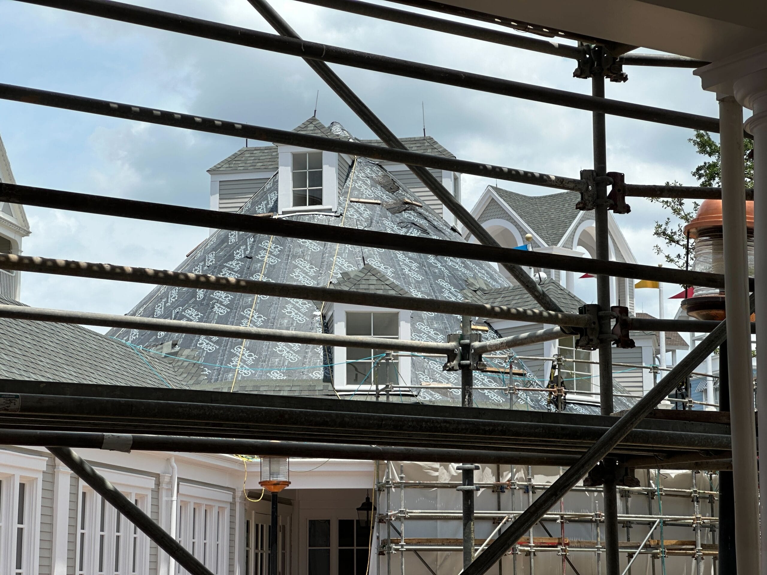 Scaffolding in front of a large house under construction, with roofing materials visible on the steep roof.