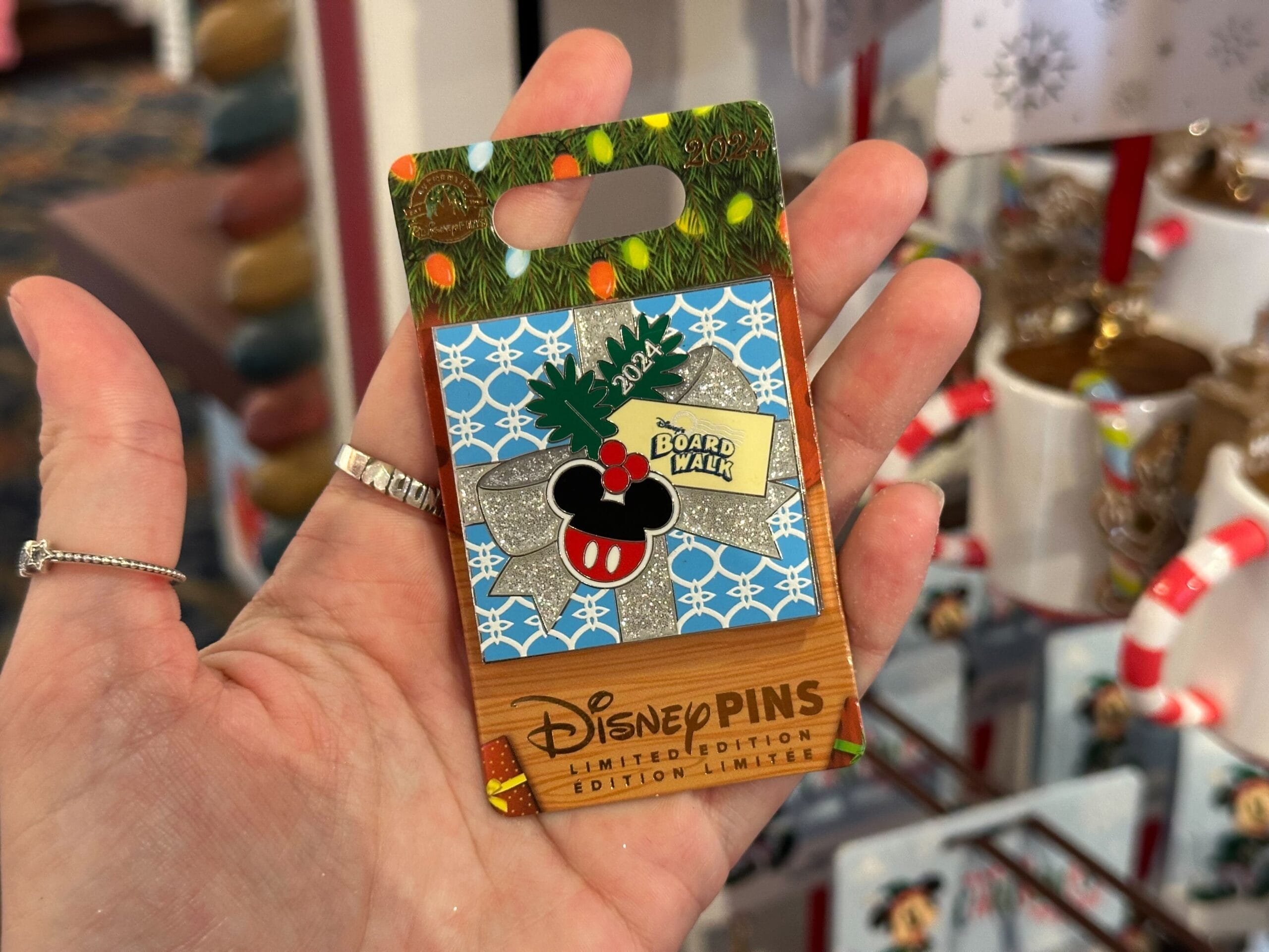 Person holding a Disney limited edition holiday pin with a Minnie Mouse design and 2023 text.