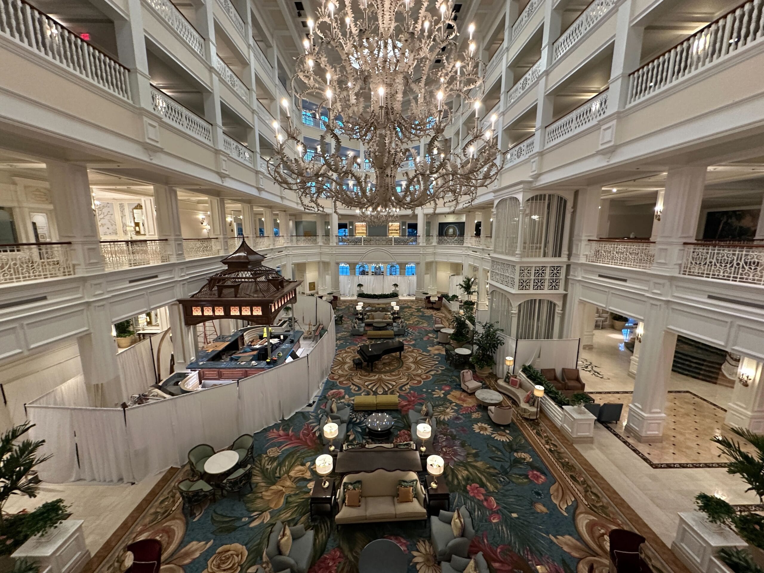 Elegant Disney resort lobby with sparkling chandeliers, ornate railings, and floral carpet by Tea Room windows, reminiscent of Grand Floridian.