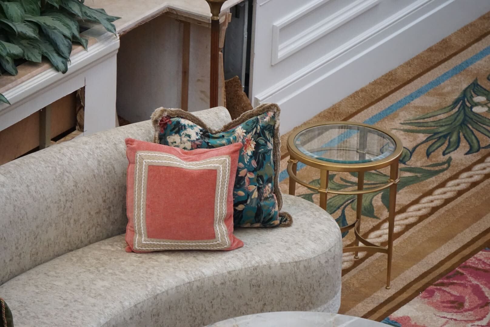 Curved beige sofa in a Disney resort lobby, two pillows, and a round glass side table placed on a patterned carpet reminiscent of Disney hotel lobbies.