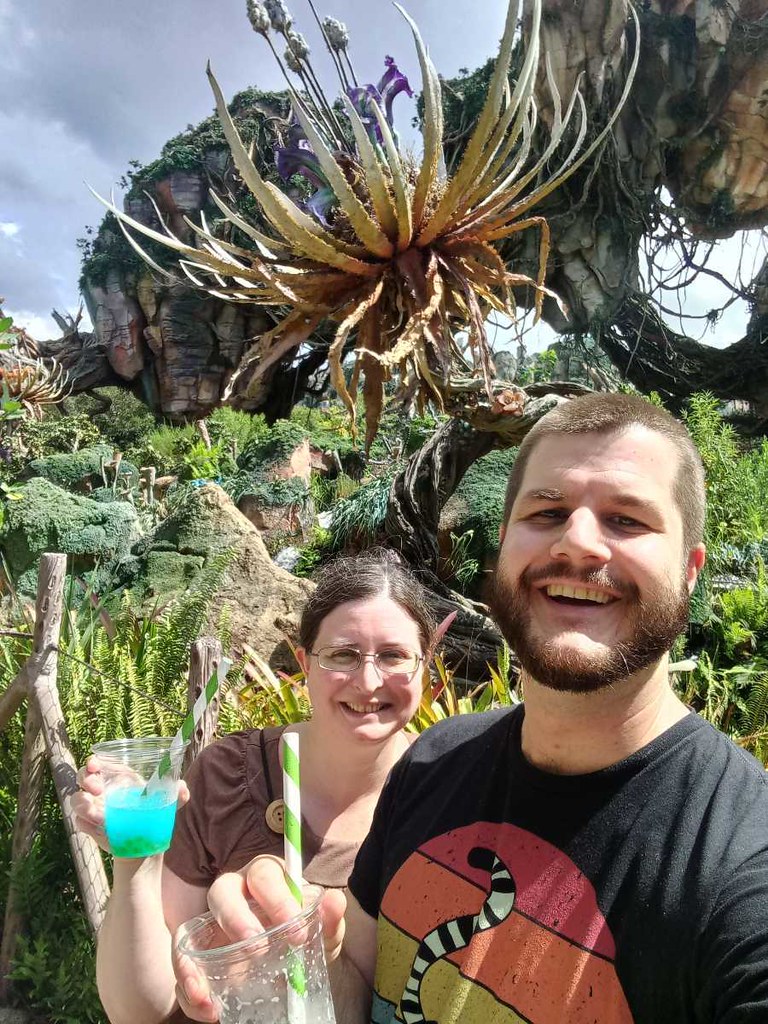 Photo of a man and woman in Pandora at Animal Kingdom holding up drinks.