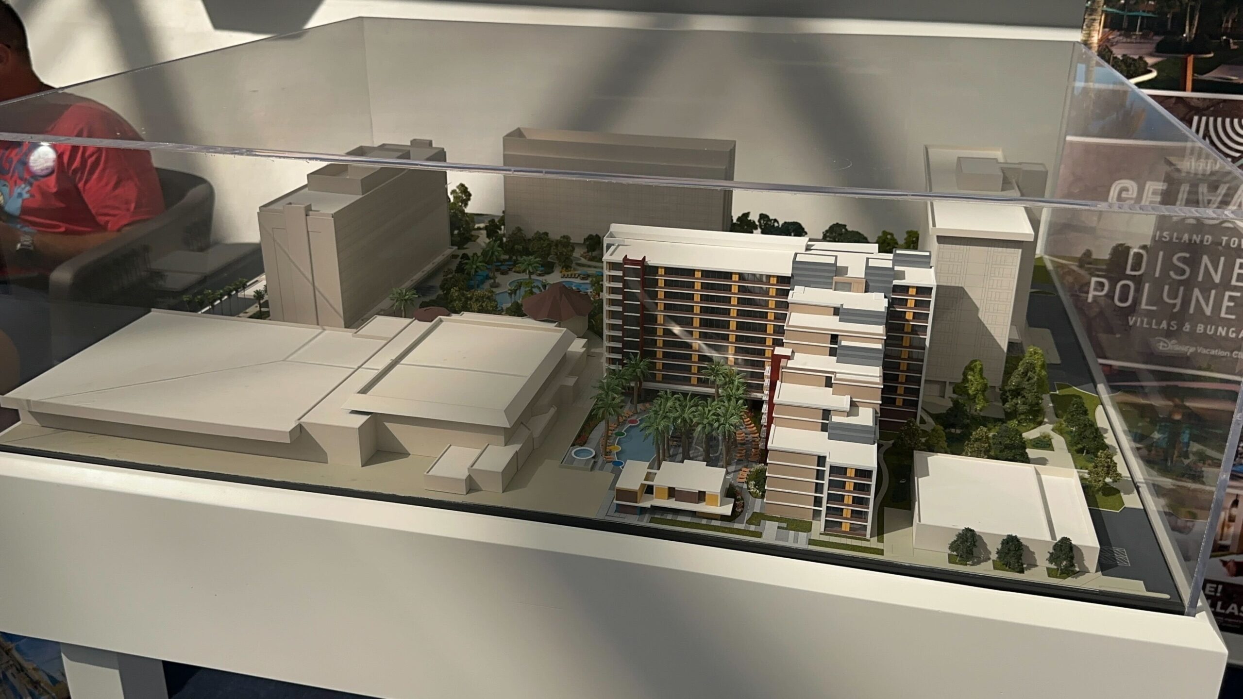 A scale model of a modern building complex on display, featuring multi-story structures, greenery, and surrounding facilities. A scale model of a modern building complex on display, featuring multi-story structures, greenery, and surrounding facilities.