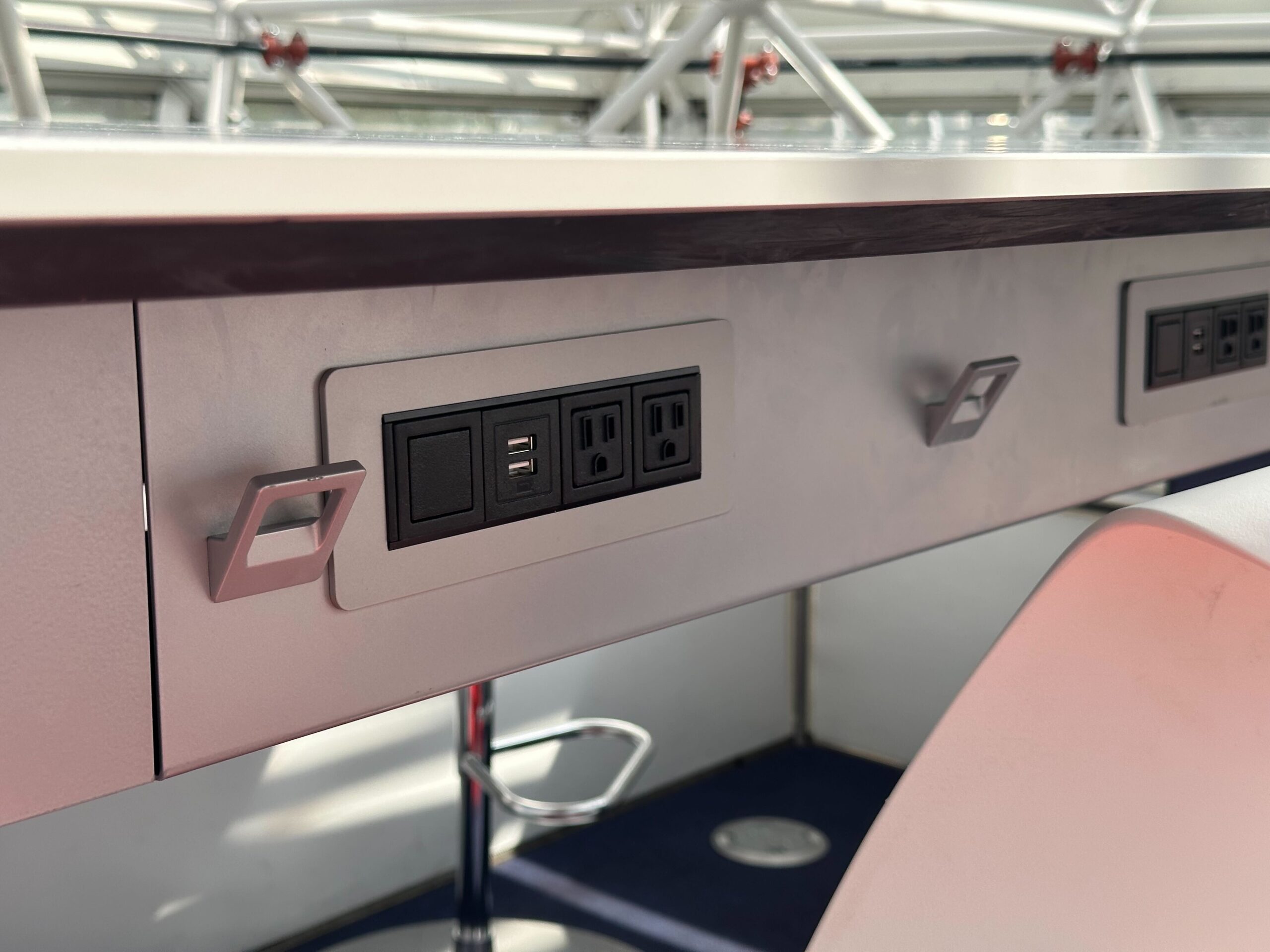 A desk with built-in power outlets and USB ports underneath in a modern setting. A desk with built-in power outlets and USB ports underneath in a modern setting.