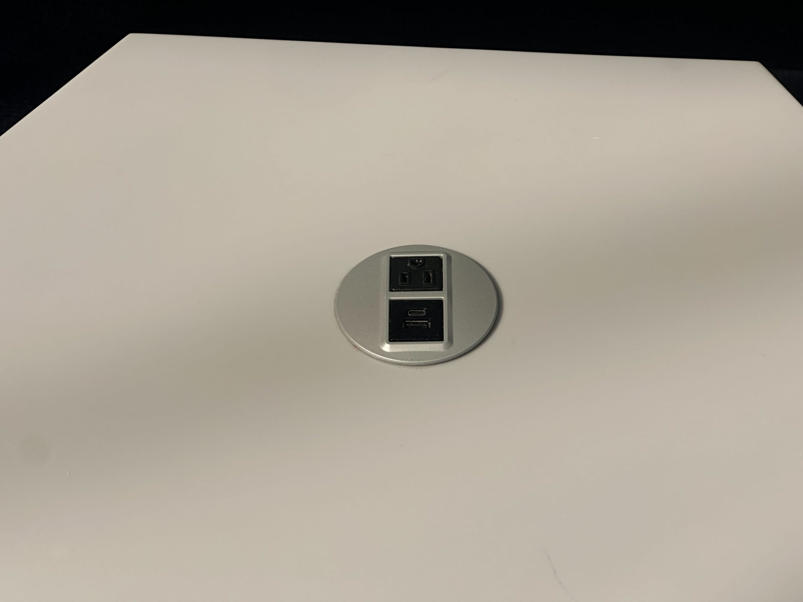 A USB and power outlet embedded in a white tabletop. A USB and power outlet embedded in a white tabletop.