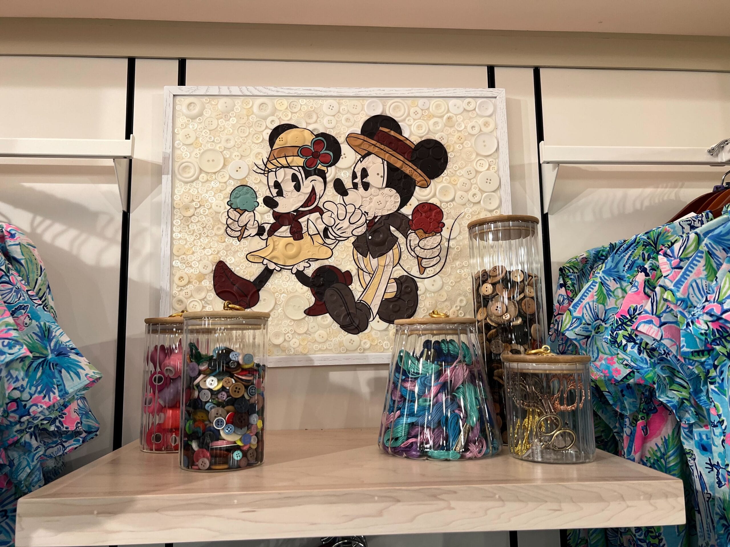 Framed Minnie and Mickey above jars of buttons on a shelf at Thimbles & Threads with patterned shirts. Framed Minnie and Mickey above jars of buttons on a shelf at Thimbles & Threads with patterned shirts.