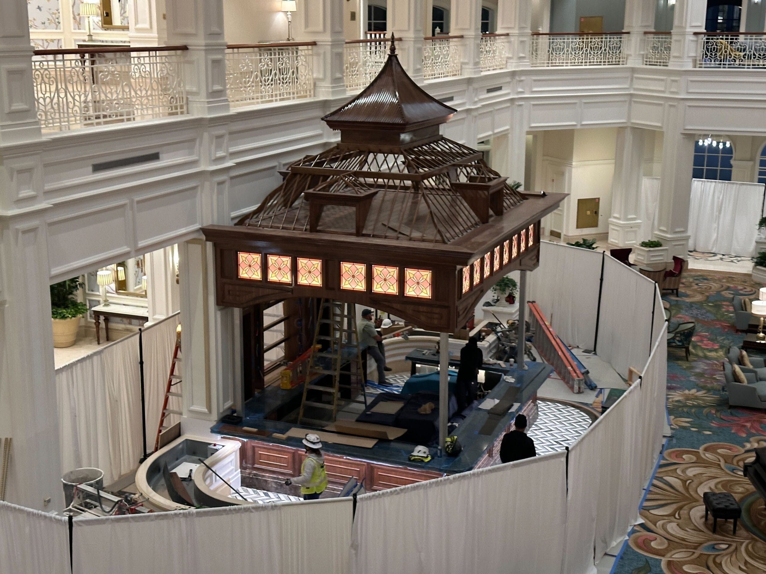 A wooden gazebo under construction in the Grand Floridian lobby at Walt Disney World, hidden behind white privacy curtains. A wooden gazebo under construction in the Grand Floridian lobby at Walt Disney World, hidden behind white privacy curtains.