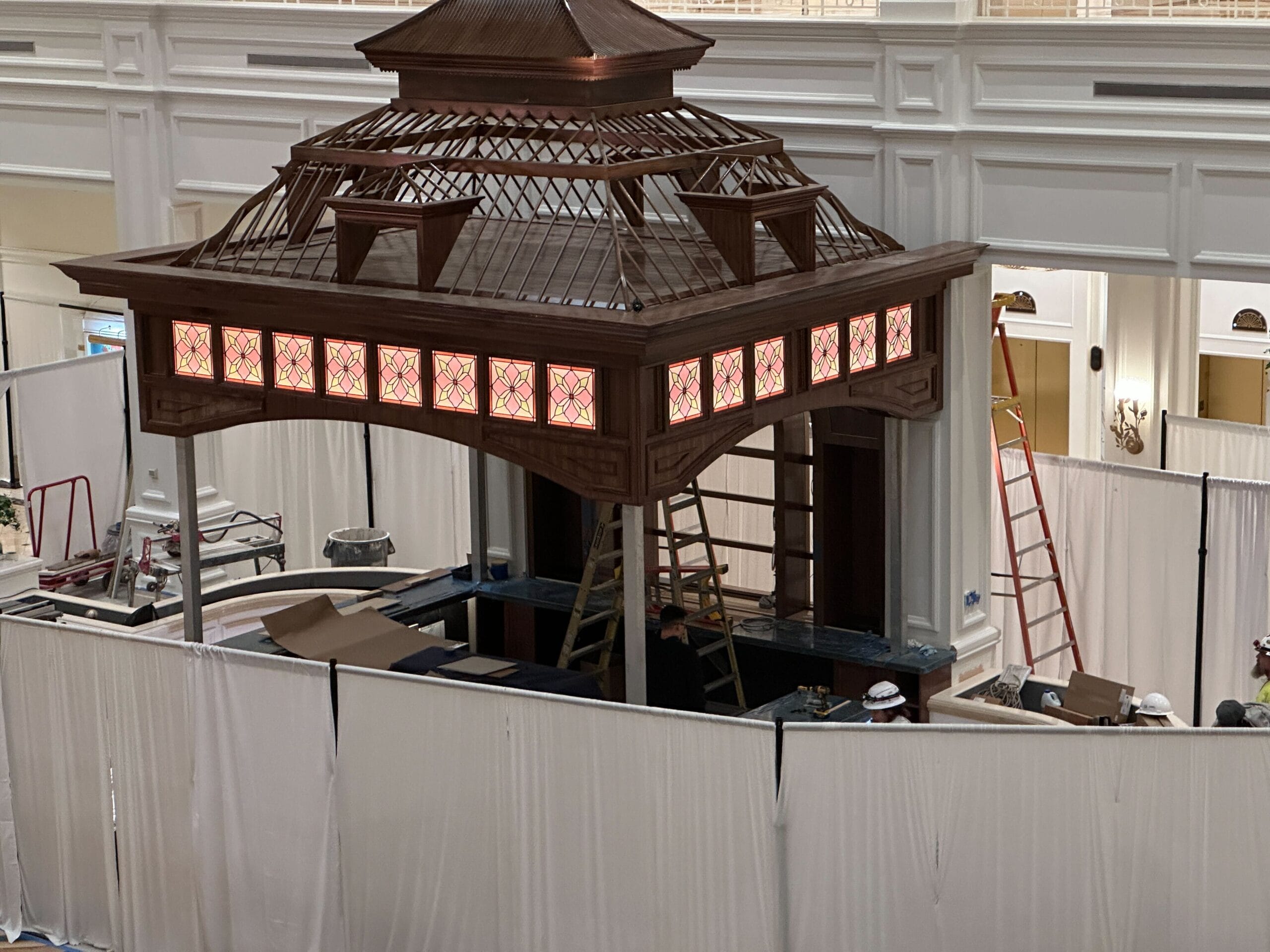 Wooden gazebo being built at Grand Floridian, white curtains and ladders present, Birdcage Bar’s stained glass glowing nearby. Wooden gazebo being built at Grand Floridian, white curtains and ladders present, Birdcage Bar’s stained glass glowing nearby.