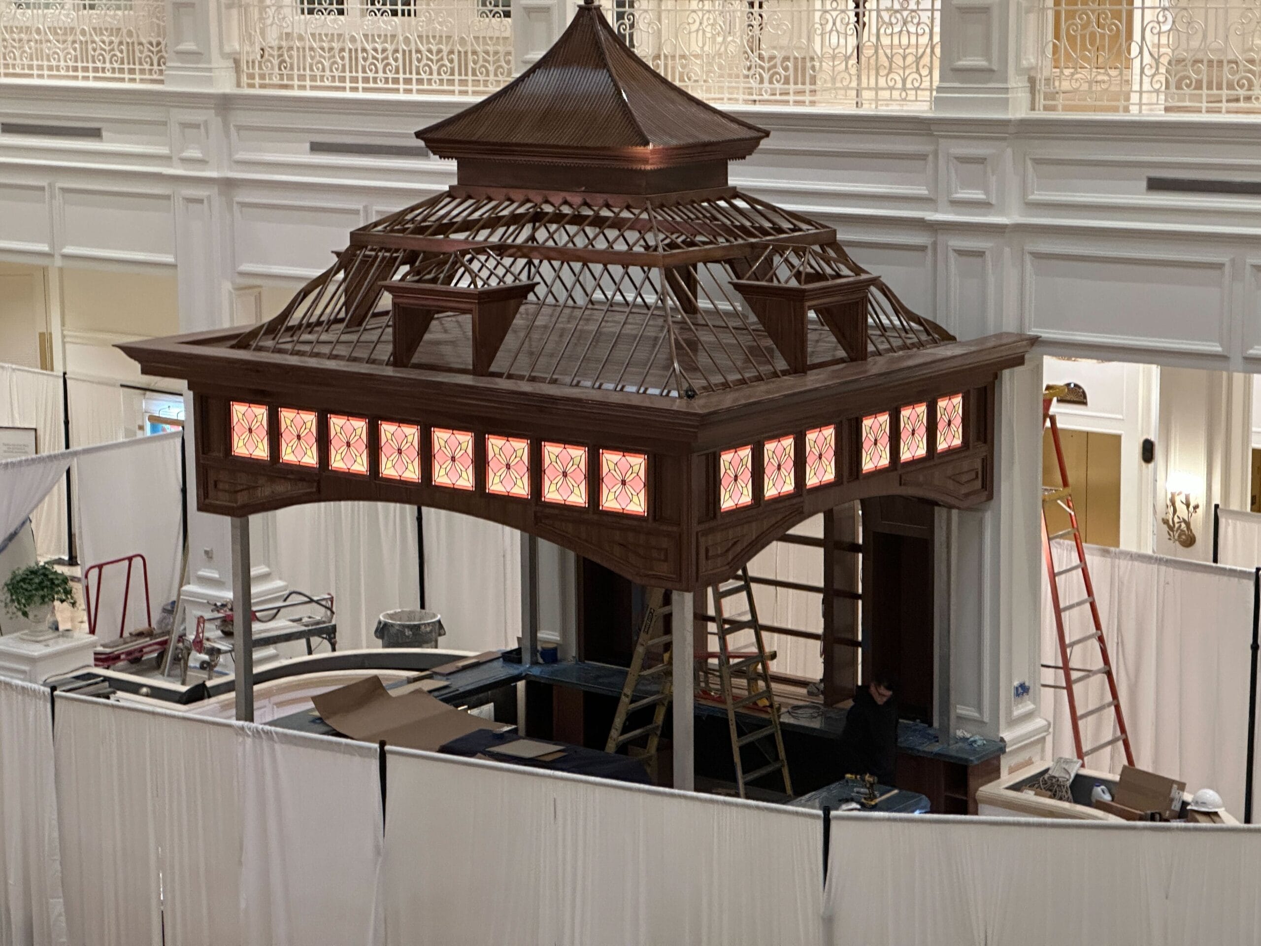 A wooden gazebo being built indoors near Birdcage Bar at a Disney's Grand Floridian, tools and curtains around. A wooden gazebo being built indoors near Birdcage Bar at a Disney's Grand Floridian, tools and curtains around.