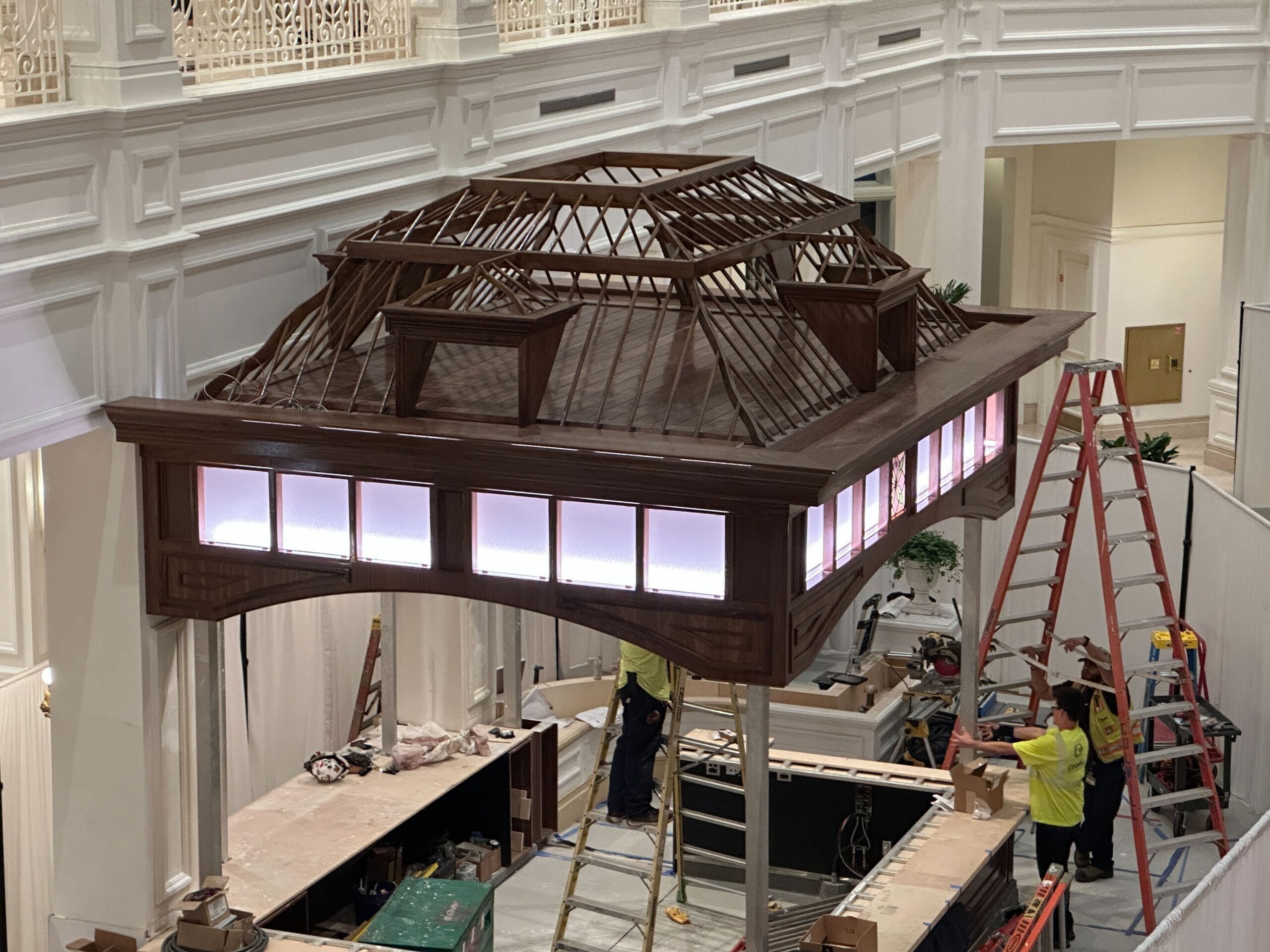 Workers on ladders build a large open-roofed wooden structure indoors at Grand Floridian, part of lobby renovations with new lighting. Workers on ladders build a large open-roofed wooden structure indoors at Grand Floridian, part of lobby renovations with new lighting.