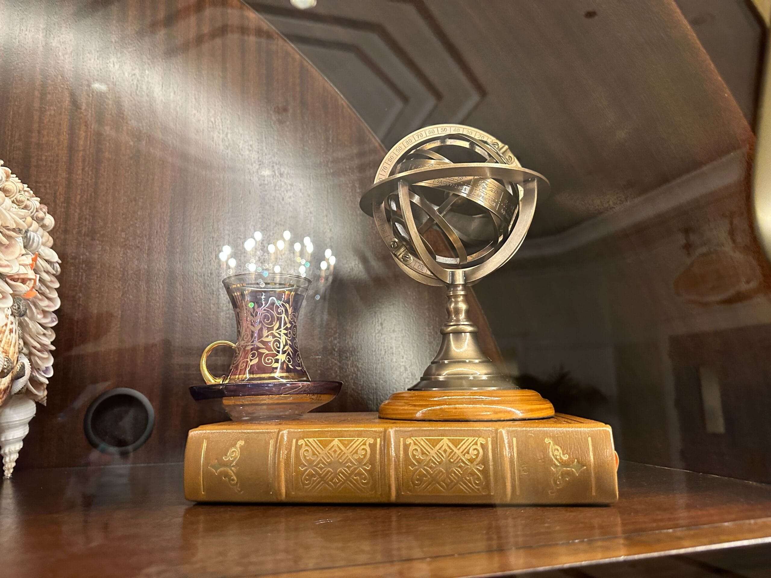 A decorative metal armillary sphere glimmers under soft lighting in a glass-front display case in the refurbished Grand Floridian lobby bar. A decorative metal armillary sphere glimmers under soft lighting in a glass-front display case in the refurbished Grand Floridian lobby bar.
