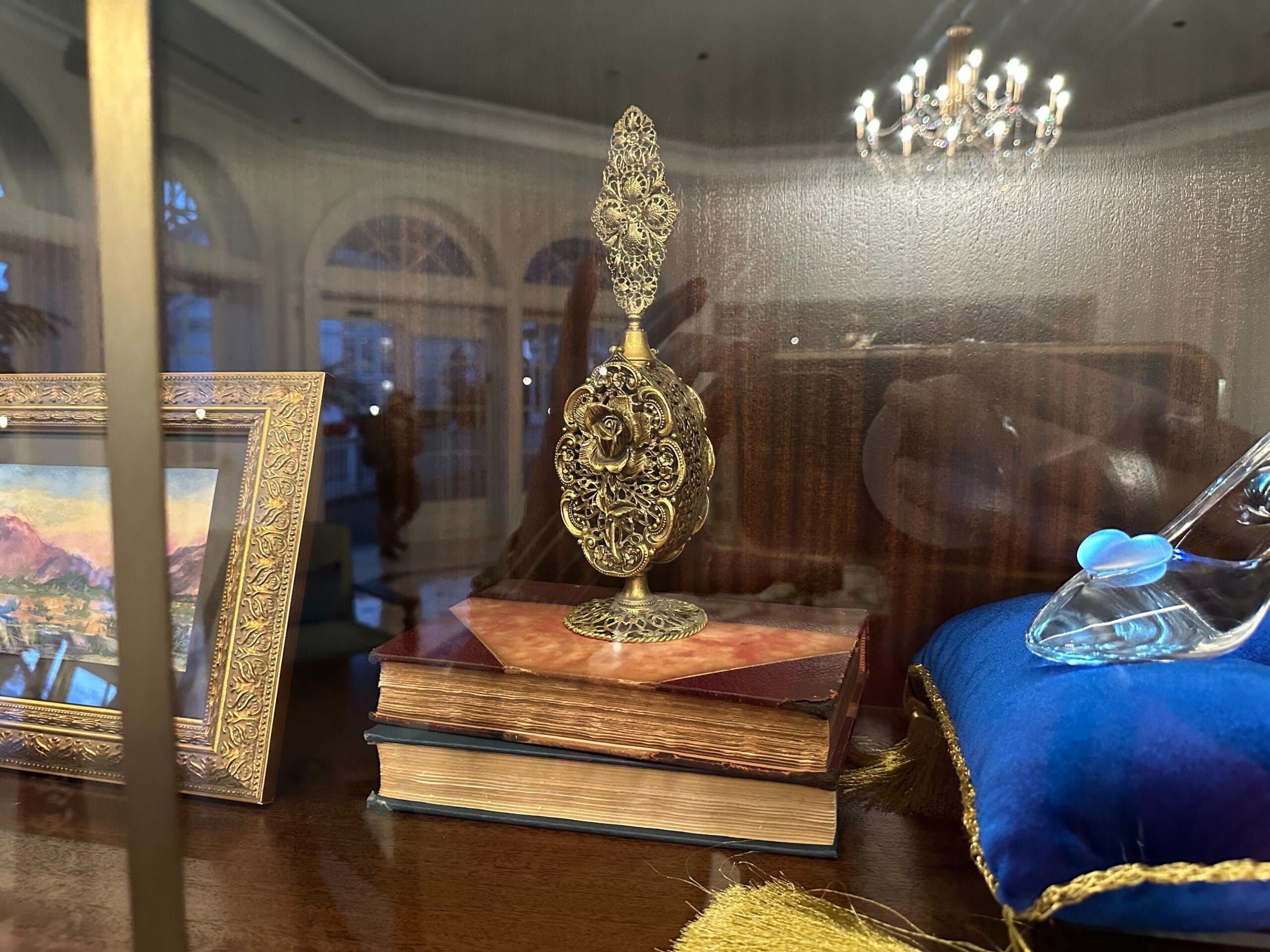Ornate golden perfume bottle atop stacked books in a glass-front display case in the refurbished Grand Floridian lobby bar. Ornate golden perfume bottle atop stacked books in a glass-front display case in the refurbished Grand Floridian lobby bar.