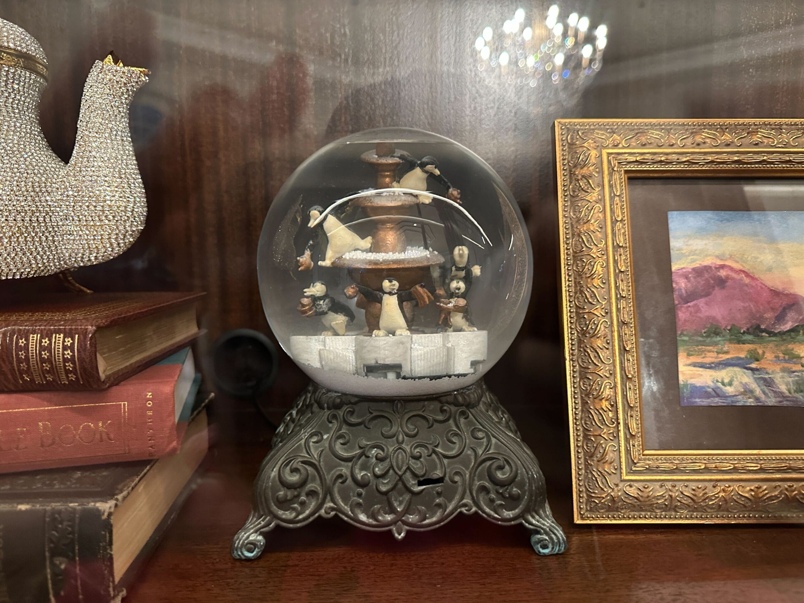 A snow globe with penguins rests on a detailed stand in a glass-front display case in the refurbished Grand Floridian lobby bar. A snow globe with penguins rests on a detailed stand in a glass-front display case in the refurbished Grand Floridian lobby bar.