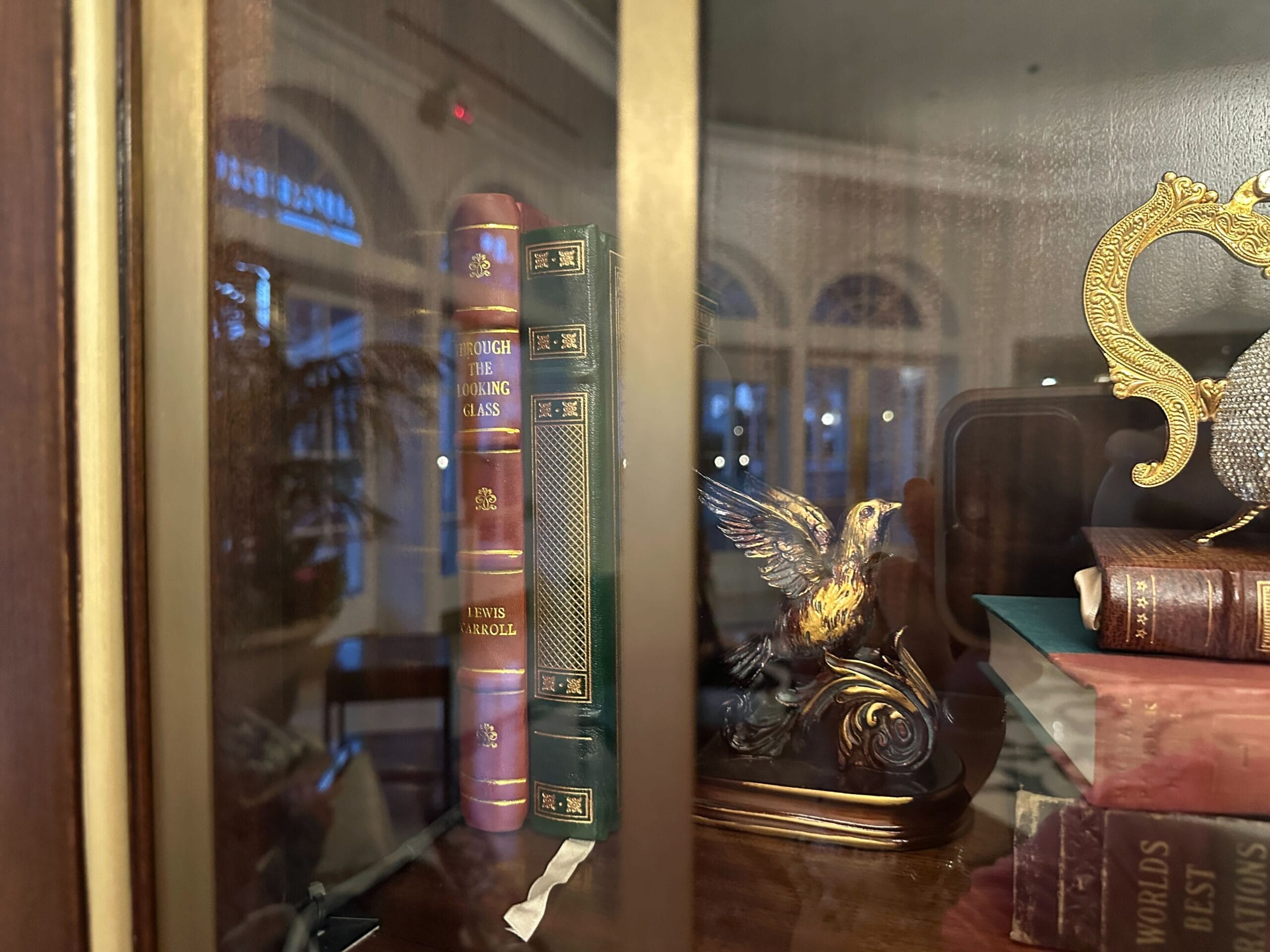 Books and a golden bird figurine shine behind glass in a display case in the refurbished Grand Floridian lobby bar. Books and a golden bird figurine shine behind glass in a display case in the refurbished Grand Floridian lobby bar.