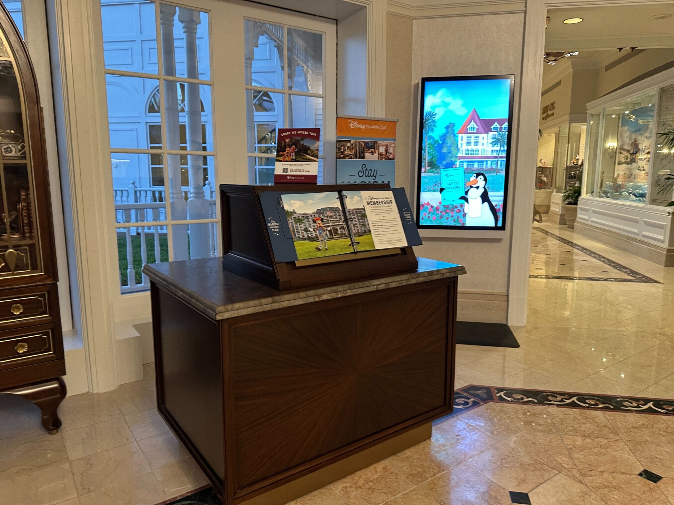 A wooden kiosk with Disney Vacation Club brochures sits in the brightly lit Grand Floridian Resort lobby. A wooden kiosk with Disney Vacation Club brochures sits in the brightly lit Grand Floridian Resort lobby.