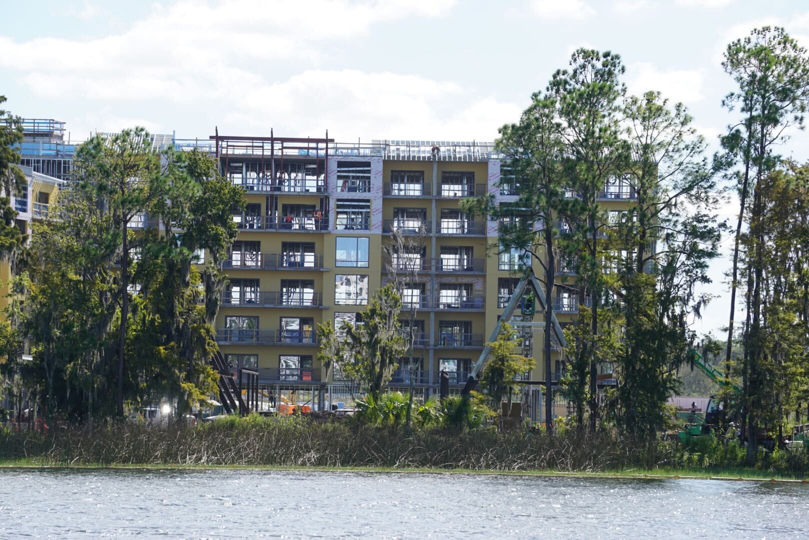 Lakeshore Update: A multi-story building rises behind trees by the water, reminiscent of Disney resort hotels, on a partly cloudy day. Lakeshore Update: A multi-story building rises behind trees by the water, reminiscent of Disney resort hotels, on a partly cloudy day.