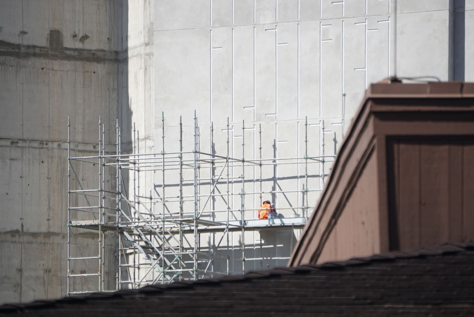 A construction worker in an orange vest stands on scaffolding during Lakeshore Update, partially hidden by a roof, no Disney castle visible. A construction worker in an orange vest stands on scaffolding during Lakeshore Update, partially hidden by a roof, no Disney castle visible.