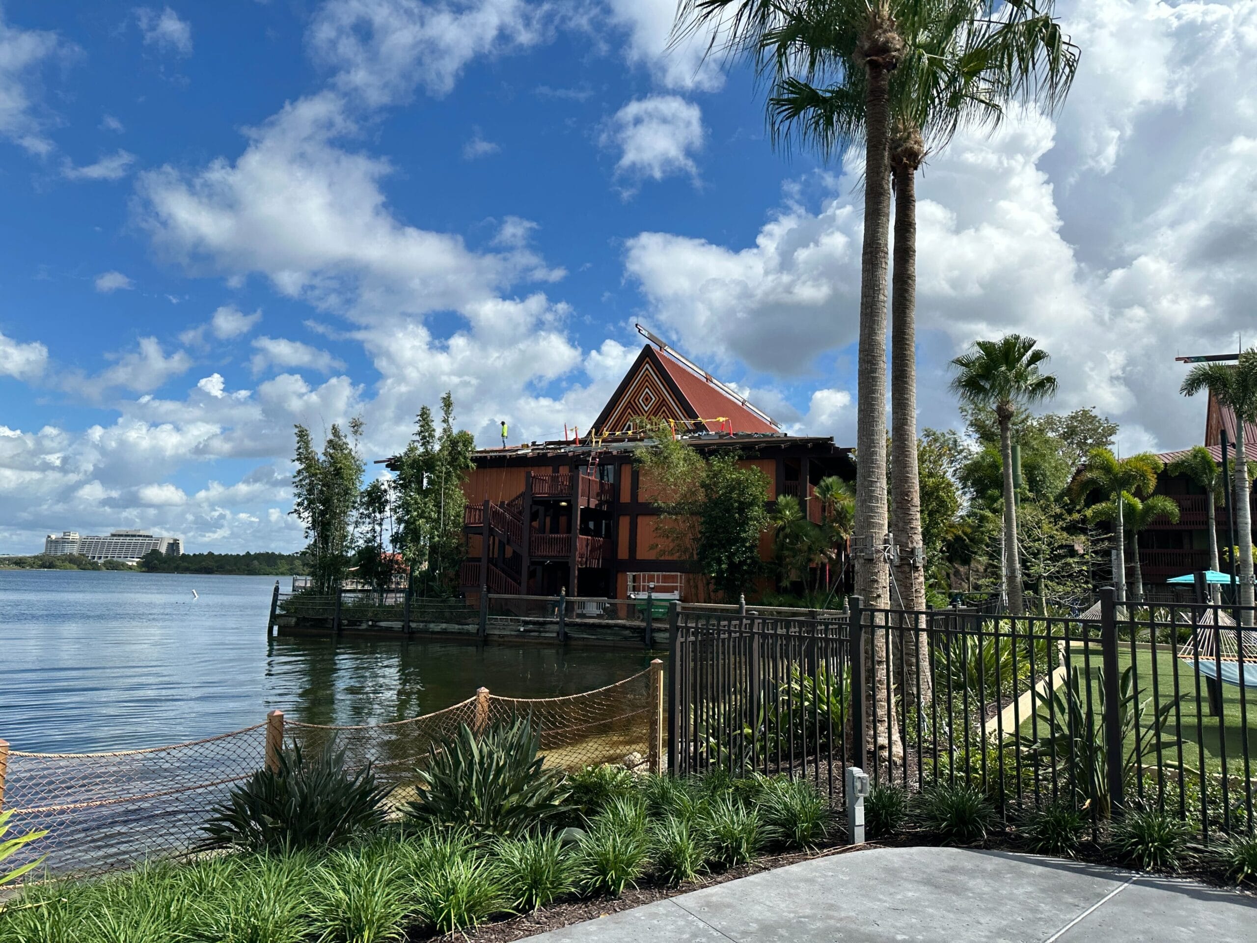 A tropical resort by a lake with palm trees and greenery, evoking Disney’s Polynesian Village vibe, under a partly cloudy sky. A tropical resort by a lake with palm trees and greenery, evoking Disney’s Polynesian Village vibe, under a partly cloudy sky.