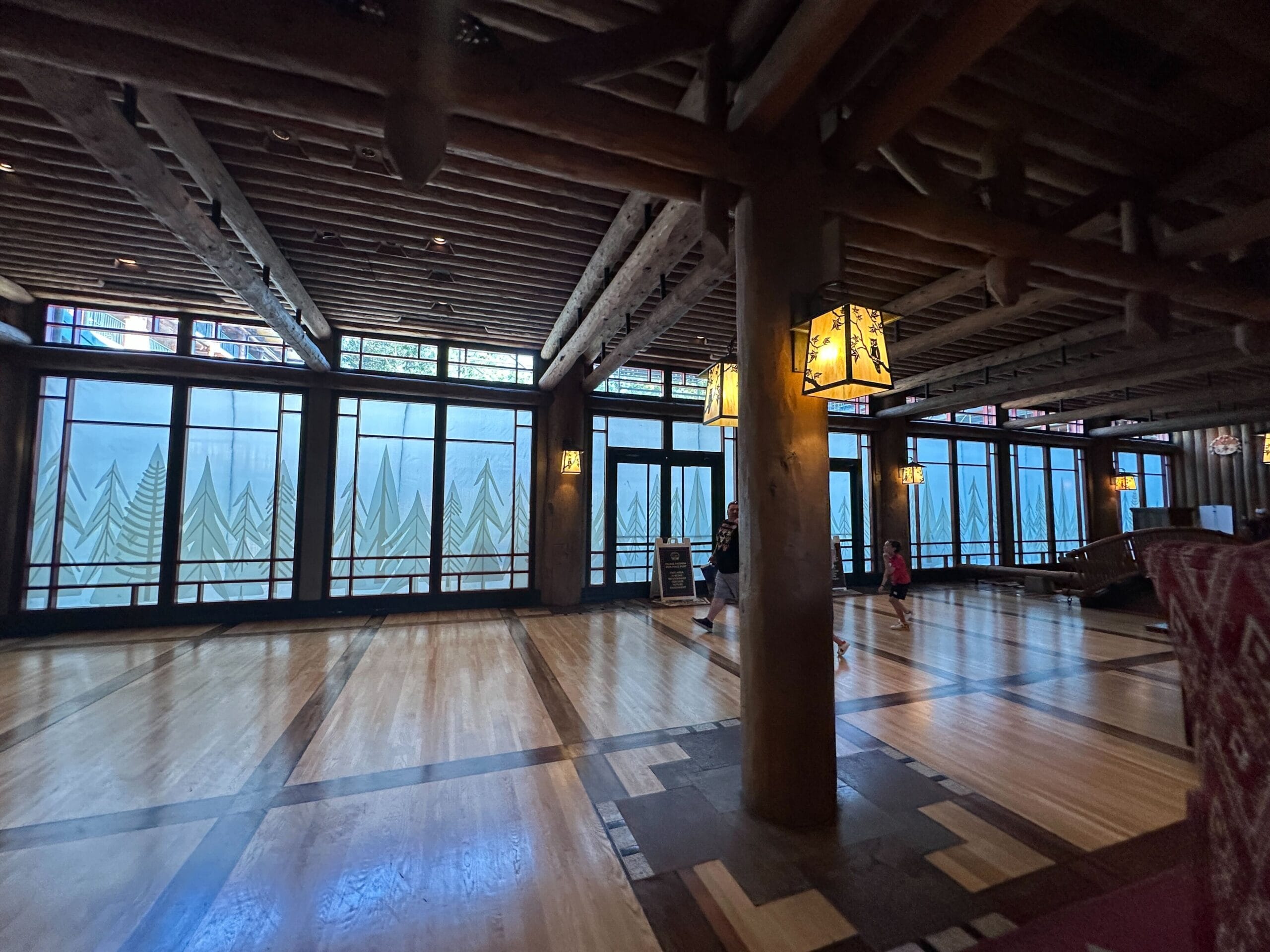 Inviting lodge lobby in Disney style, with rustic wooden beams, nature-inspired windows, soft lantern lighting, and guests strolling. Inviting lodge lobby in Disney style, with rustic wooden beams, nature-inspired windows, soft lantern lighting, and guests strolling.